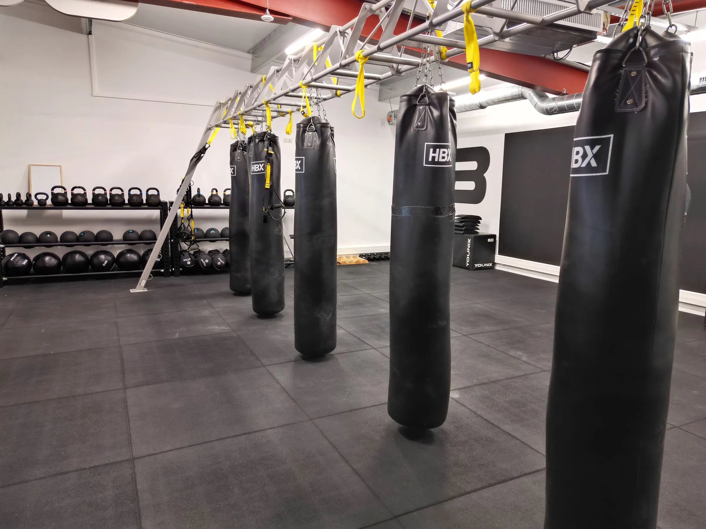 Salle avec sacs de frappes et altères